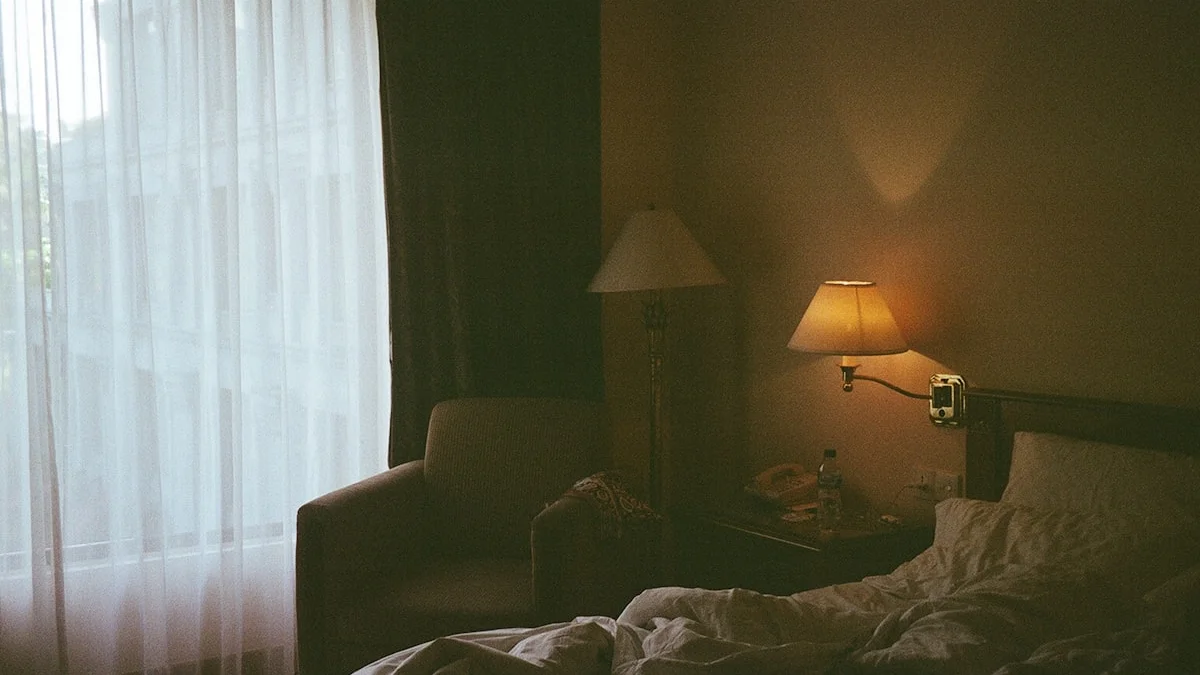 An armchair faces a bright window beside a warm lamp in a dim room. — a The Obsidian Key guide to The Assumption Seat: Ten Minutes of Occupation.