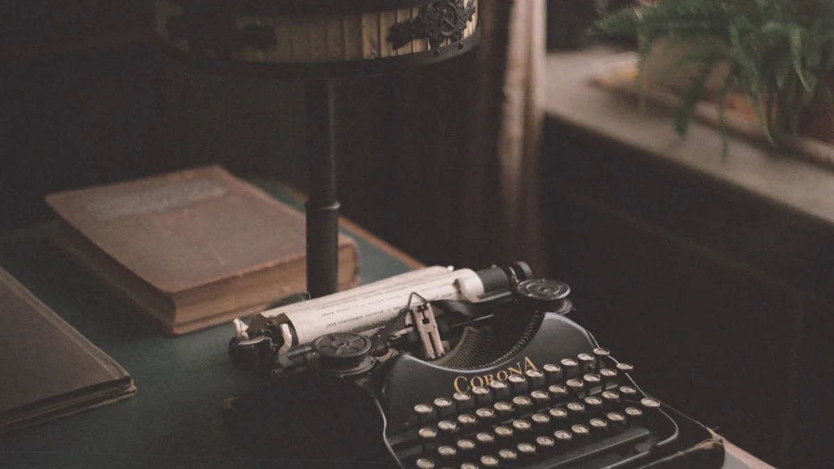 Vintage Corona typewriter under a brass desk lamp beside worn books. — a The Obsidian Key guide to Start a Beginner Manifestation Journal Tonight.