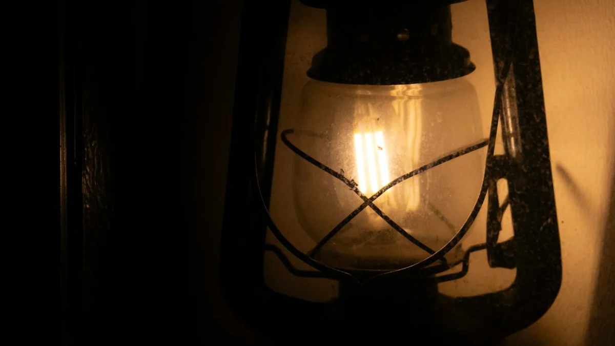 An antique hurricane lantern glowing warmly against a dark wall. — a The Obsidian Key guide to Other People's Emergencies: The Folios on Borrowed Urgency.