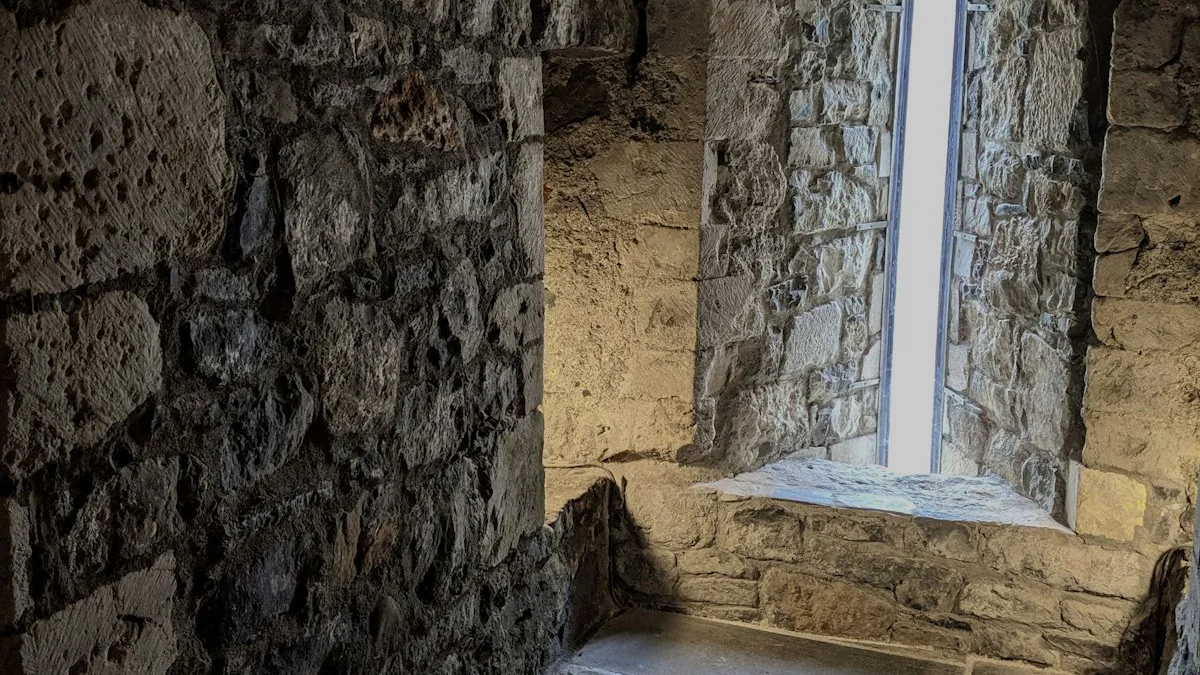 A narrow arched window lights the rough stone walls of an old vault room. — a The Obsidian Key guide to Burial by Dilution: How Gates Absorb Leaks.