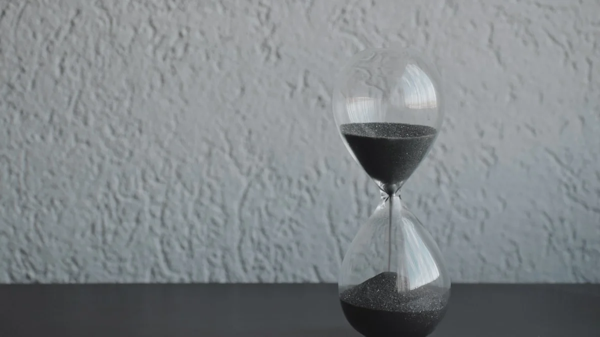 An hourglass with dark sand running stands on a dark desk against a pale plaster wall. — a The Obsidian Key guide to Emotional Regulation at Work: Holding the Room.