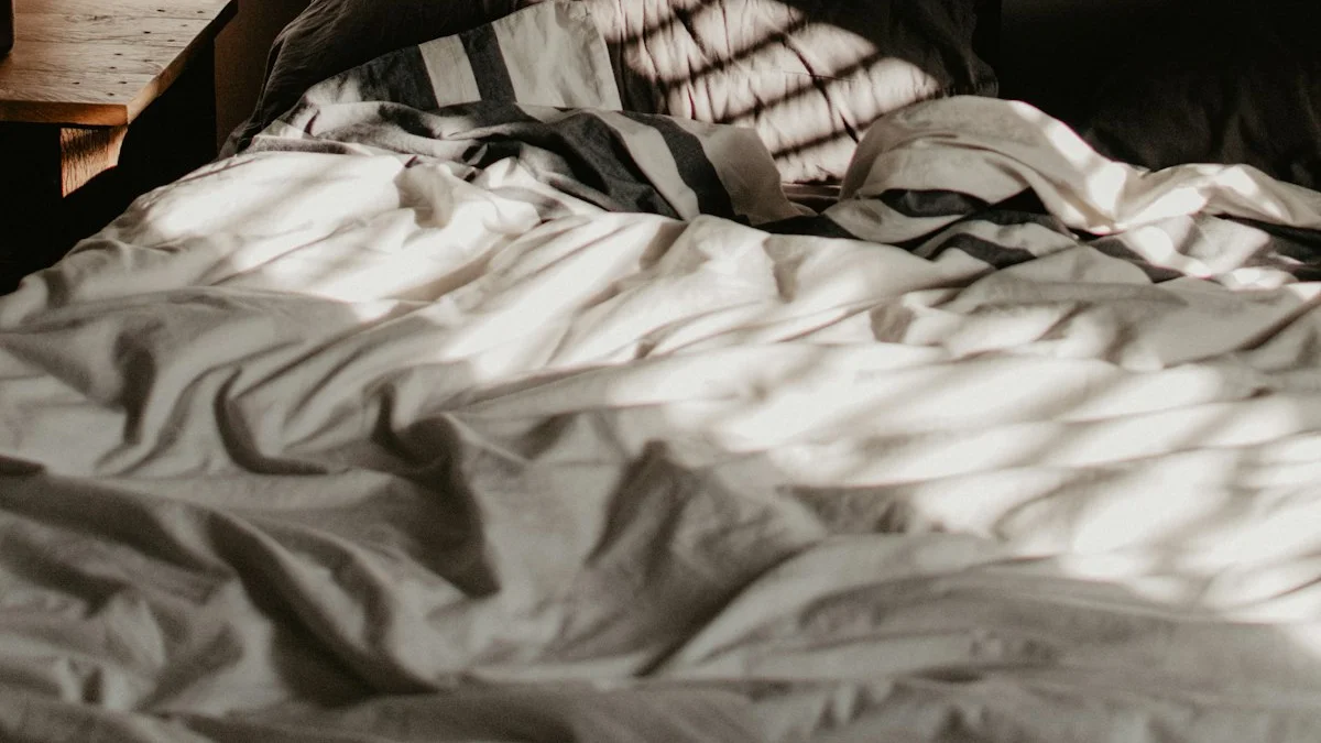 An unmade bed with rumpled striped sheets catches gray morning light in a dark quiet bedroom. — a The Obsidian Key guide to When Sleep Does Not Fix Your Exhaustion.