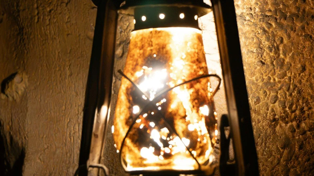 A glowing antique lantern mounted on a dark stone wall. — a The Obsidian Key guide to Fear and the Field: Why Alarm Matches Alarm.