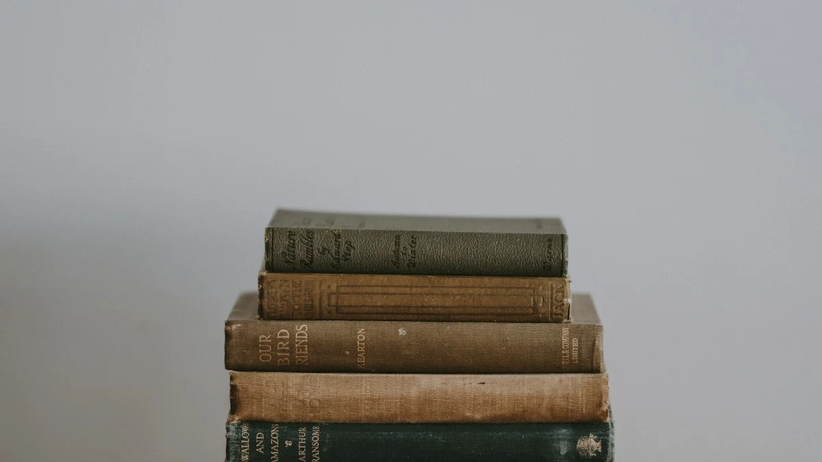 A small stack of worn clothbound books against a plain grey background. — a The Obsidian Key guide to Fluency Is Not Progress: the Reader Who Collects.