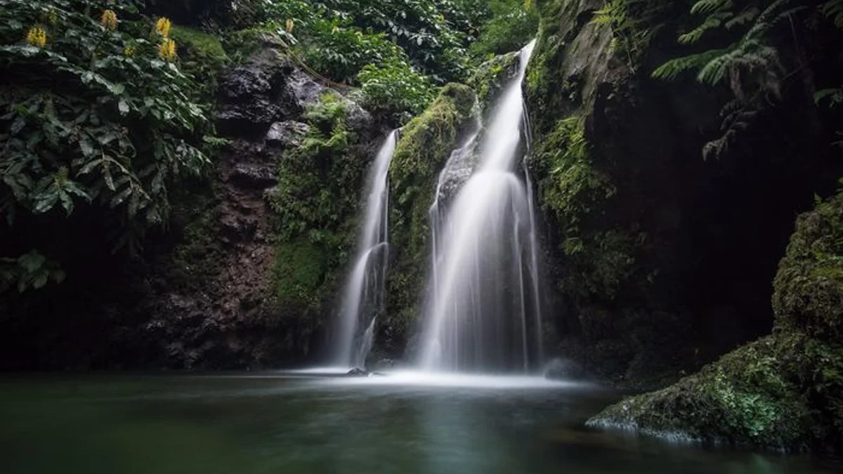 A long-exposure waterfall pours over green moss into a still, dark pool. — a The Obsidian Key guide to Laws Three and Four Together: Seal Then Compound.