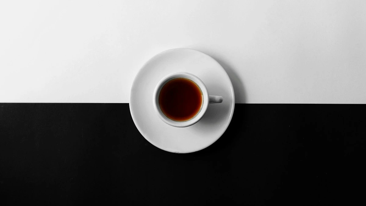 A white coffee cup on a saucer centered on a table split between black and white. — a The Obsidian Key guide to Manifestation Beginner Self-Check: Start Here.