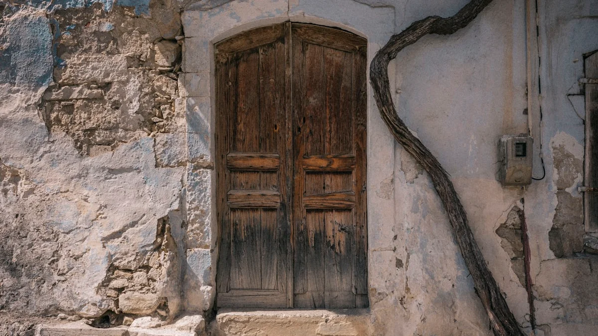 A weathered wooden double door set in a crumbling plastered wall with stone steps. — a The Obsidian Key guide to Manifestation Without Pretending or Performing.