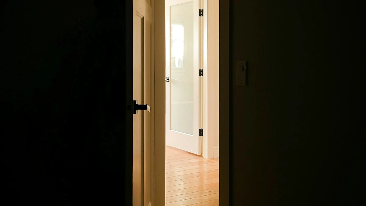 An open door in a dark hallway with warm lamplight spilling from a bright room beyond. — a The Obsidian Key guide to The Next Sentence: Choosing a New State After Day 21.