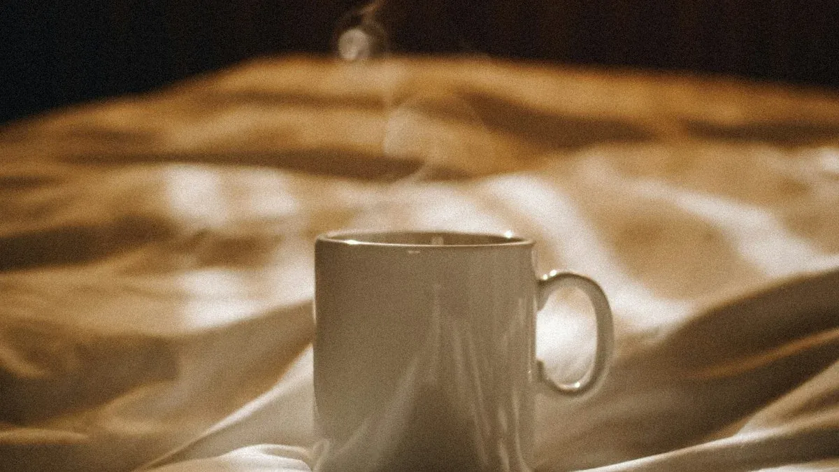 A steaming mug resting on rumpled bedding in warm golden morning light. — a The Obsidian Key guide to The First Hour: Why No Phone Before the Seat.