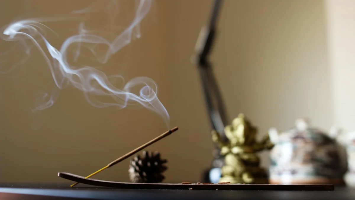 A thin stick of incense smolders on a dark table, a ribbon of smoke rising through a warm quiet room. — a The Obsidian Key guide to Outrage: The Costliest Emotion per Minute.