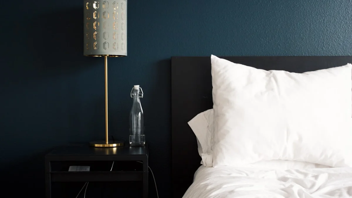 A brass lamp glows on a nightstand beside a turned-down bed in a dark blue bedroom. — a The Obsidian Key guide to Parasite Audit Self-Check: Who Owns Your Evenings.