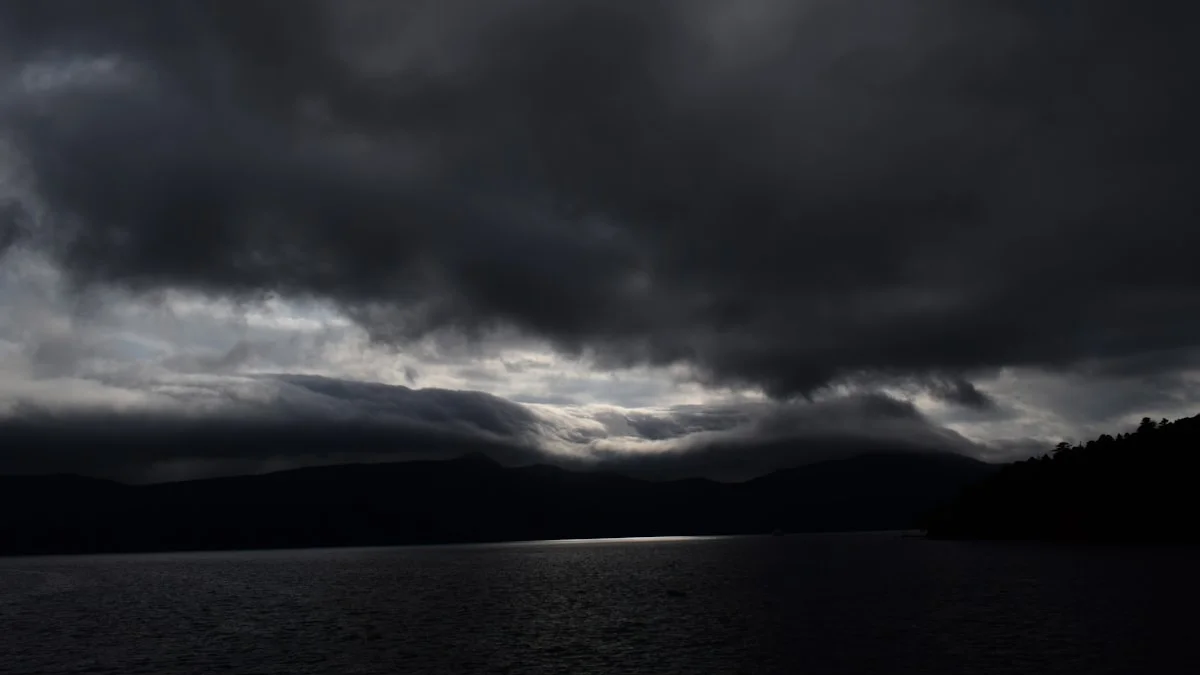 Heavy storm clouds gathering over dark, flat water at dusk. — a The Obsidian Key guide to Reading Your Emotional Weather Without Blame.