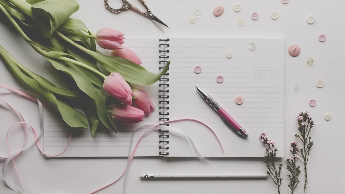 An open lined notebook with a pen beside pink tulips and ribbons on a white table. — a The Obsidian Key guide to Five Relationship Mistakes New Practitioners Make.
