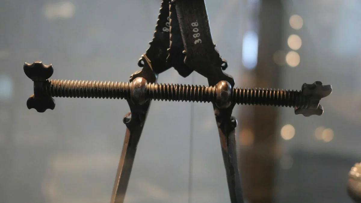 An antique brass caliper with two arms hangs by a wire in front of soft bokeh lights. — a The Obsidian Key guide to Remove or Time-Box: The Two Remedies for Leaks.
