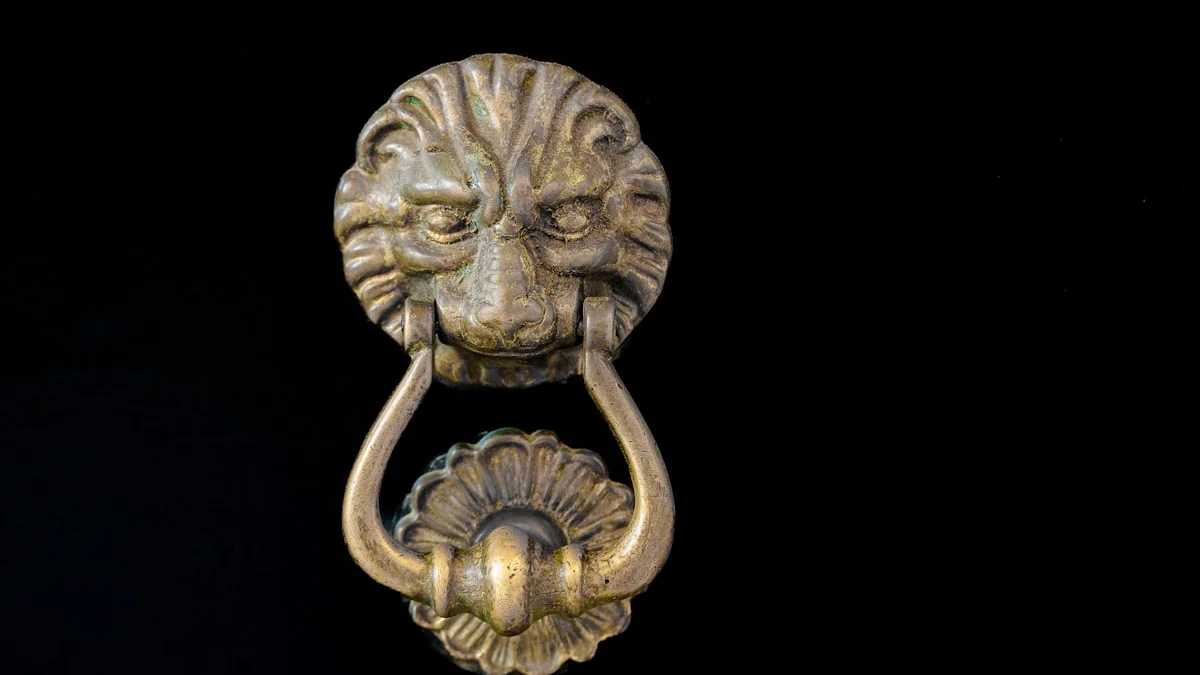 An antique brass lion head door knocker mounted on a black door. — a The Obsidian Key guide to Stop Explaining Yourself: The Attention Cost of Persuasion.