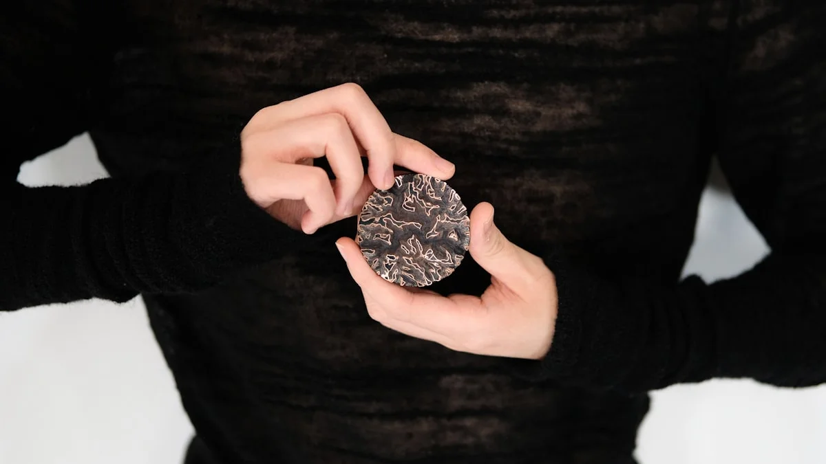Hands in a dark sweater quietly holding a small carved disc. — a The Obsidian Key guide to The Invisible Hand: Moved Not Driven.