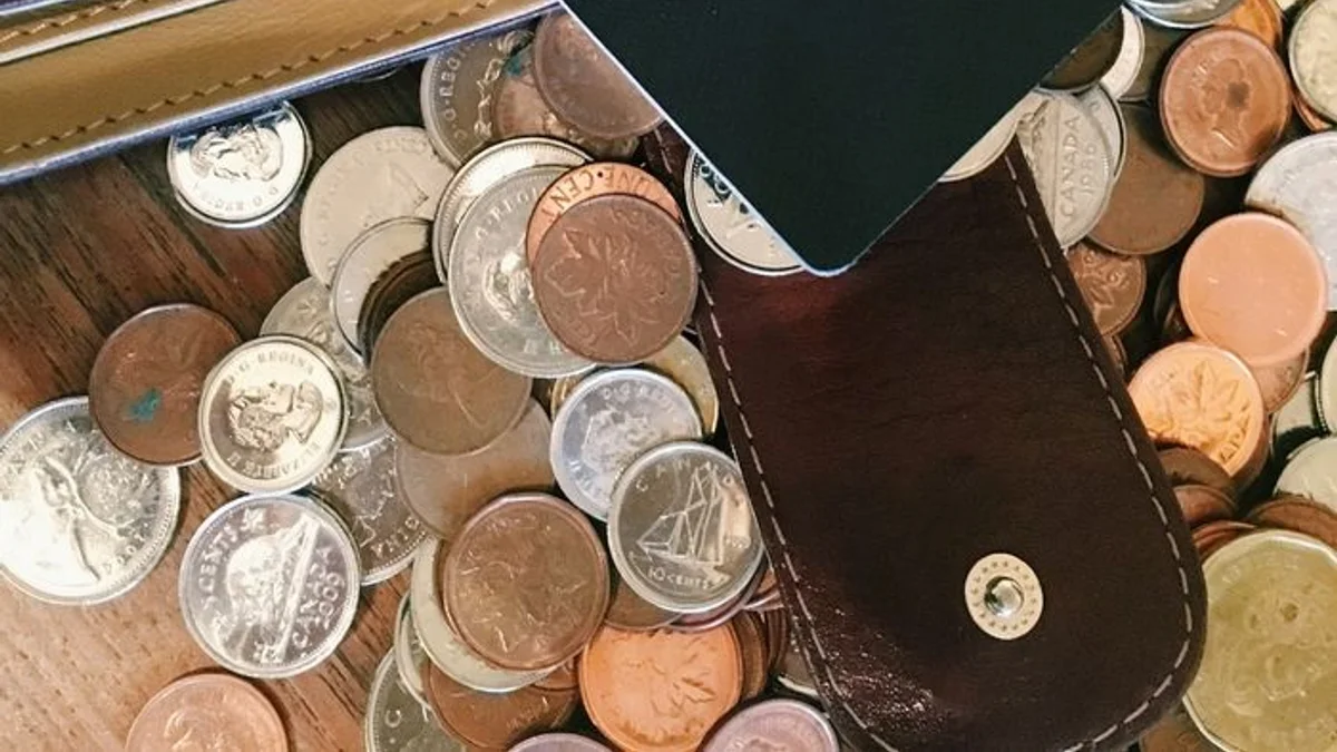 A spread of old coins and an open leather wallet on a worn wooden table. — a The Obsidian Key guide to The Sixth Law: The Opened Hand.