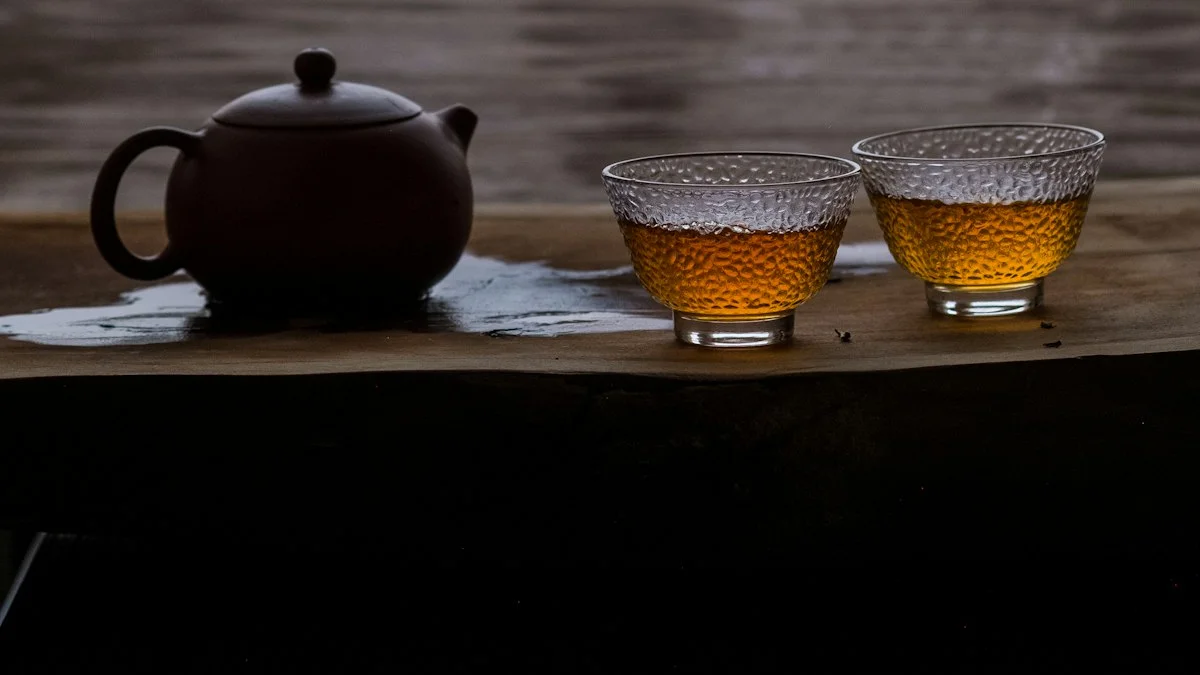 A clay teapot and two amber tea cups sit on a dark wooden board in low warm evening light. — a The Obsidian Key guide to Warmth Food Sleep: the Doctrine of Same Day Recovery.