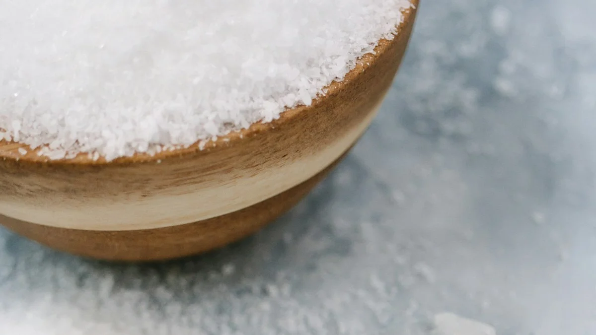 A wooden bowl of coarse salt sits on a blue-painted cloth beside quartz crystals. — a The Obsidian Key guide to What Salt Can and Cannot Do: Tools as Focus.