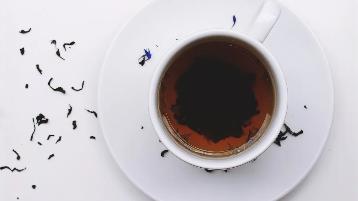 A cup of tea rests on a white table scattered with loose leaves. — a The Obsidian Key guide to When They Call You Cold: The Cost of Untouchability.